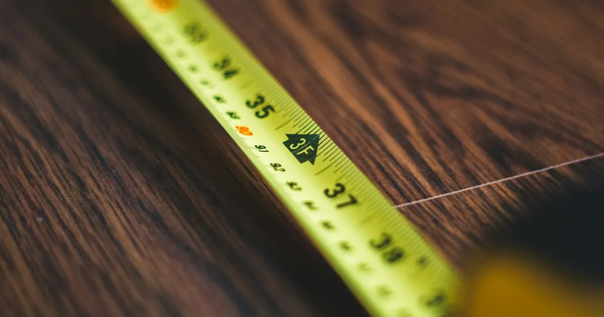 Yellow tape measure stretched across a wooden tabletop