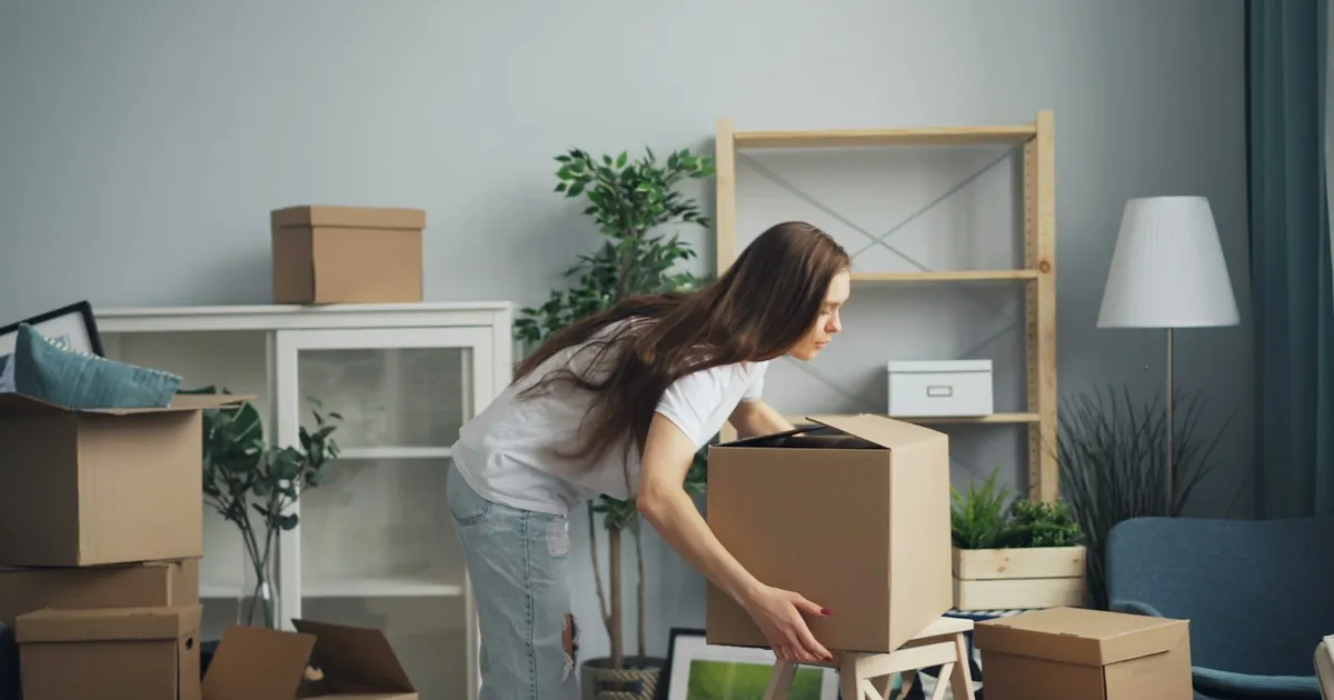 A person arranging cardboard boxes in a living room