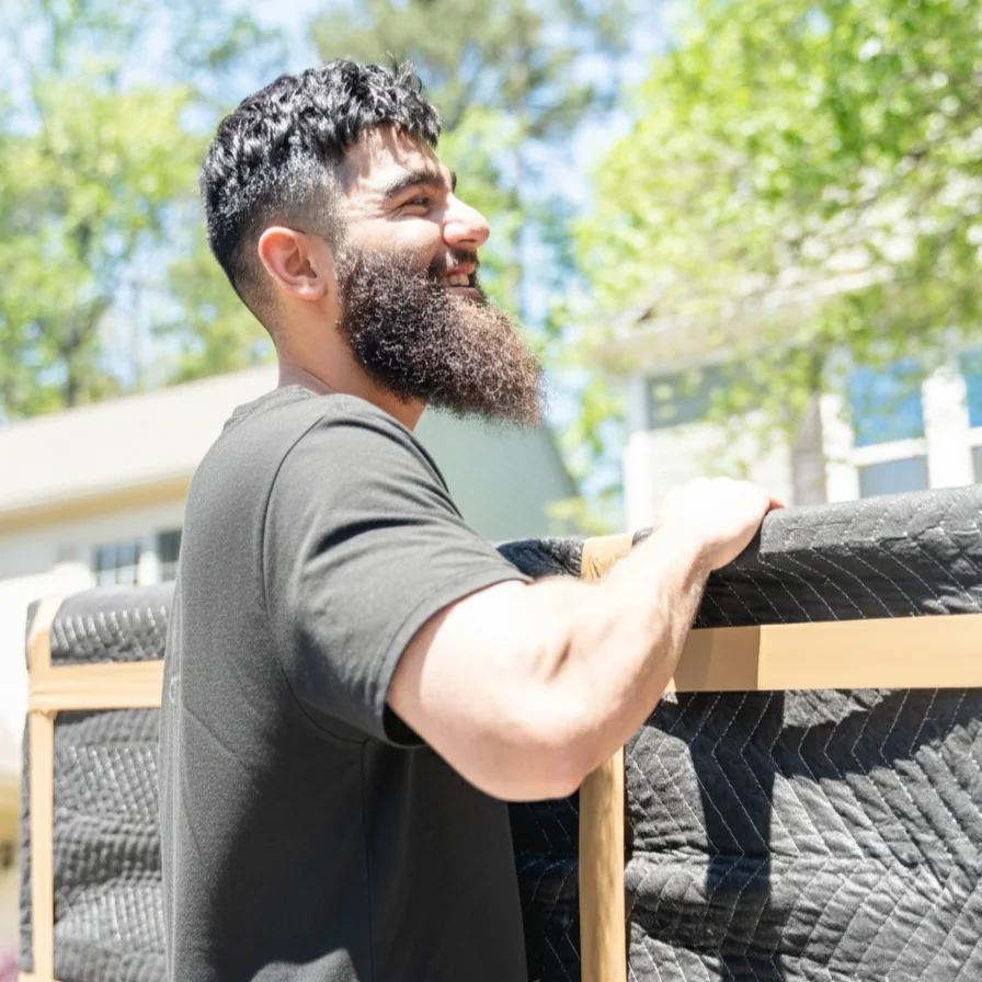 Zak moving a wrapped piece of furniture outside a home