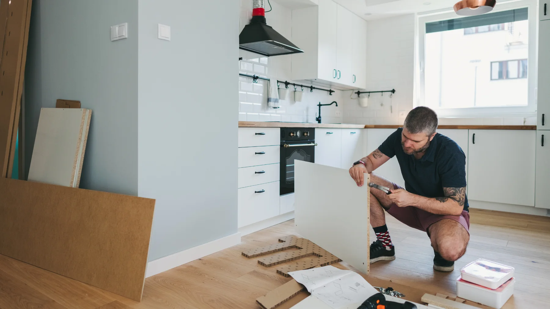 Illustrative image of a person assembling cabinetry in a bright kitchen